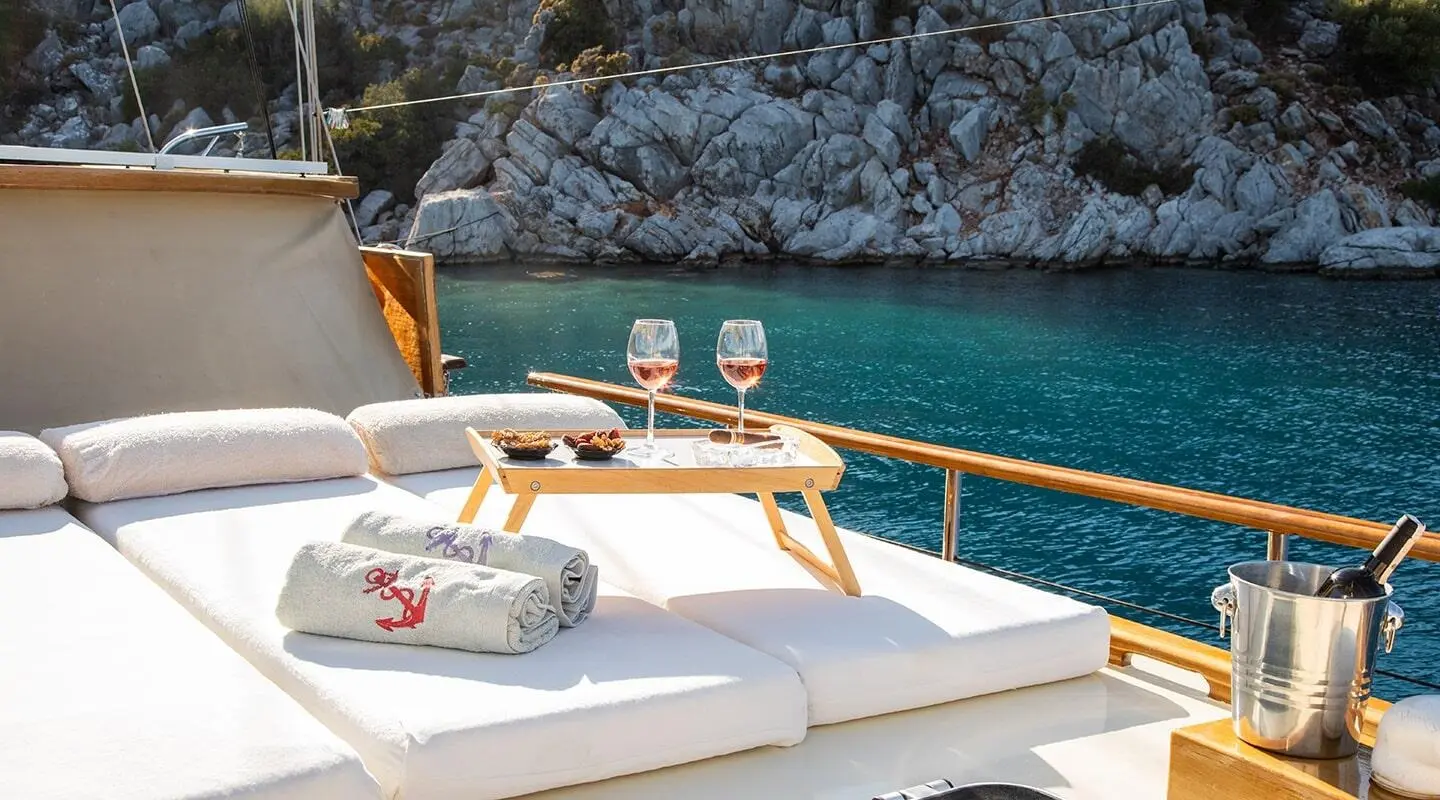 Derin Deniz yacht deck with sun loungers and glass of wine at sunset