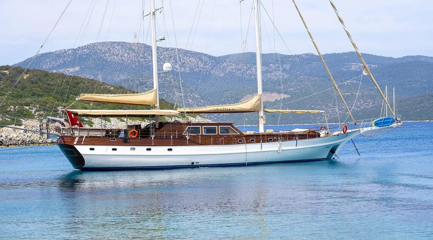 Arabella gulet anchored in calm blue waters with hills in the background