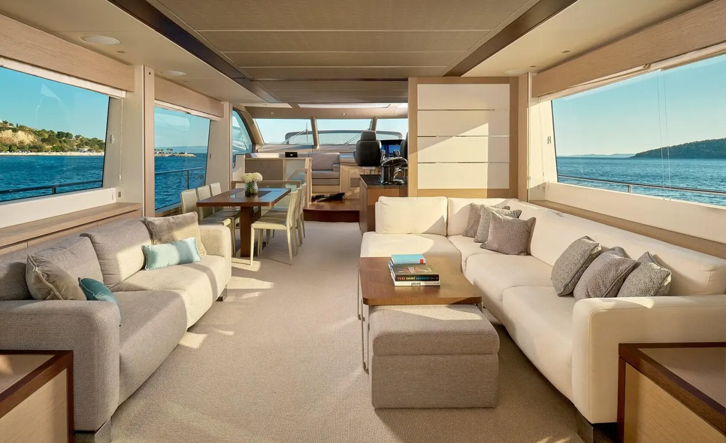 Salon deck of a yacht with seating, cushions, and windows viewing blue sea