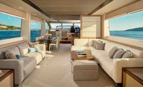 Salon deck of a yacht with seating, cushions, and windows viewing blue sea