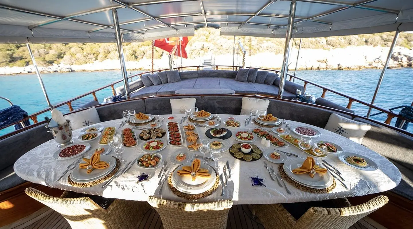 A dining table aboard Arif Kaptan A yacht, set with plates and glassware under a canopy