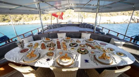 A dining table aboard Arif Kaptan A yacht, set with plates and glassware under a canopy
