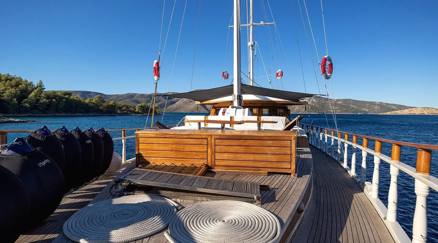 Aborda yacht deck at sunset with wooden seating and sailboat masts