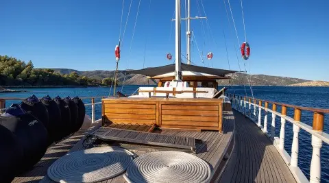 Aborda yacht deck at sunset with wooden seating and sailboat masts