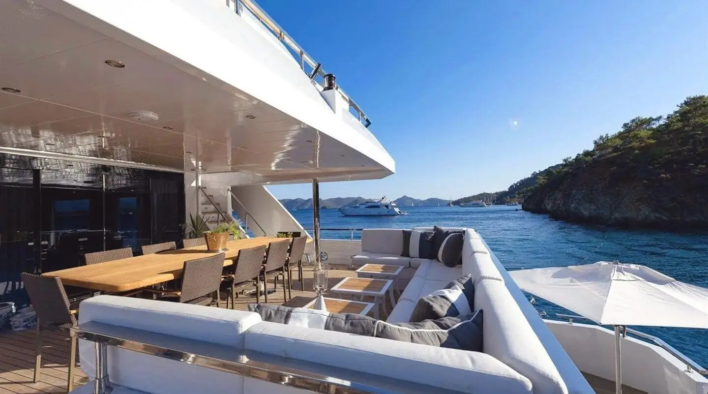 Ocean Breeze yacht deck dining area with seating, table, and view of sparkling sea