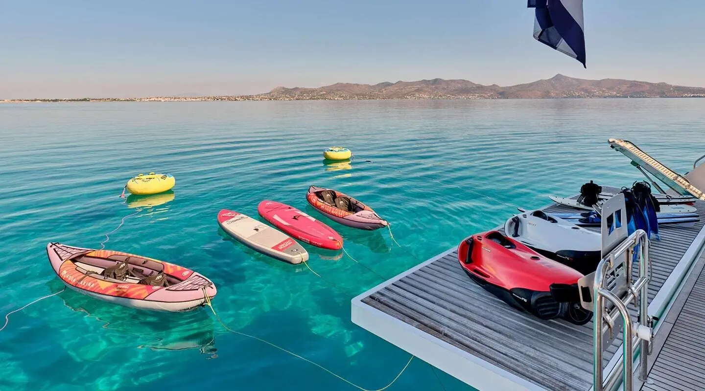 Yacht Christal Mio with colorful inflatable toy boats near a wooden platform