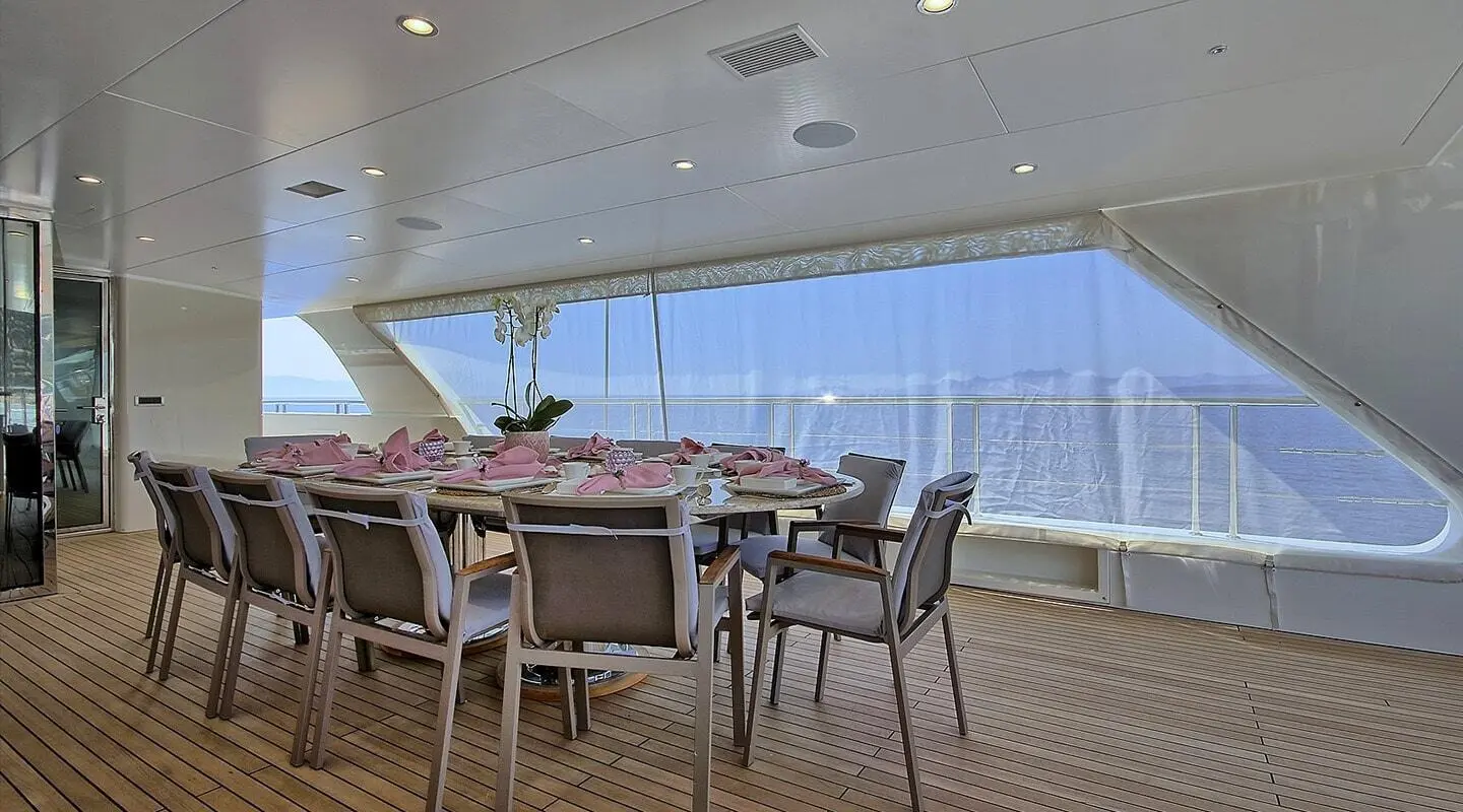 Meira yacht dining area with long table, chairs, and large windows view