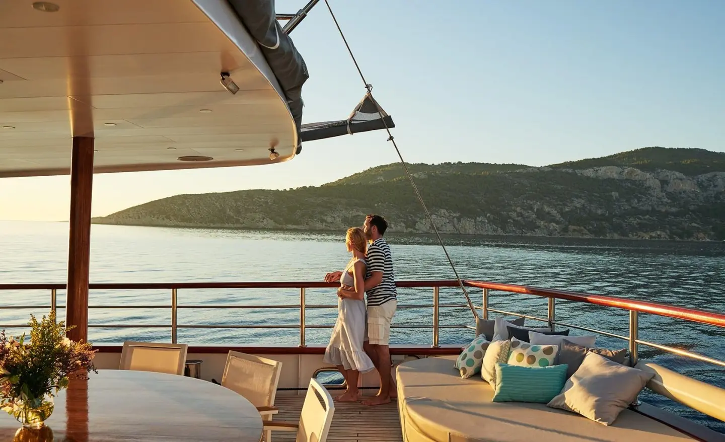 Corsario yacht on calm water at sunset with deck seating and sails