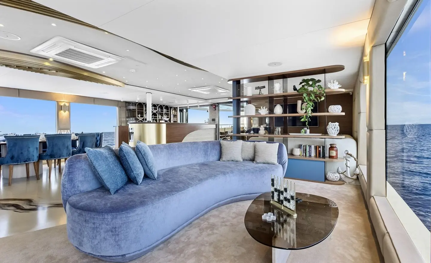 Bella yacht exterior at sunset, spacious deck, blue seating and circular glass table