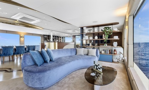 Bella luxury yacht interior with curved blue sofa, open-plan lounge and sea view