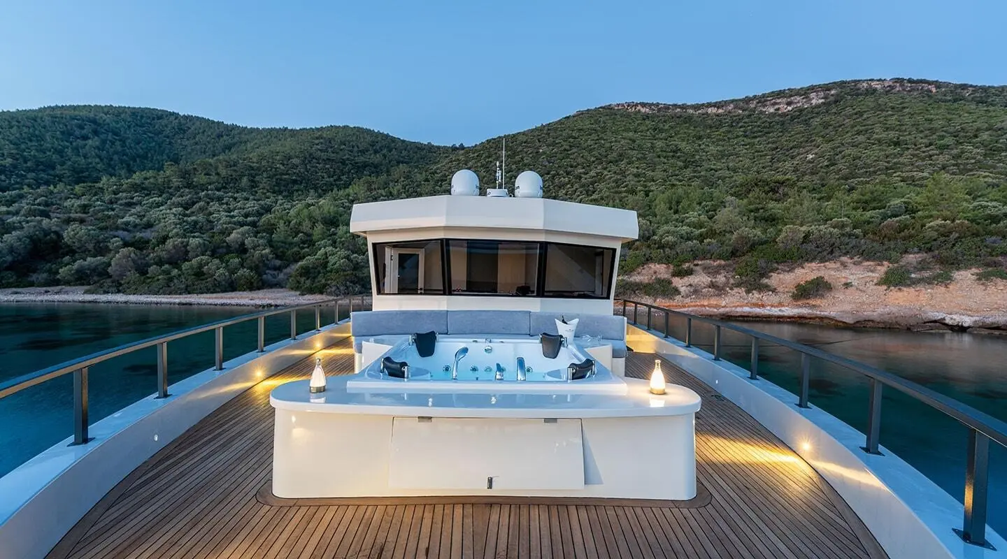 Calm Down yacht at a dock with blue water and mountains behind