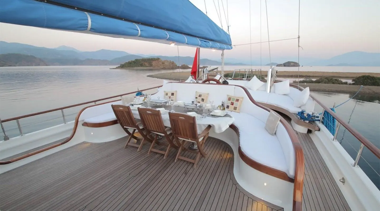 Yacht Ece Berrak deck seating area with wooden chairs at sunset on calm sea