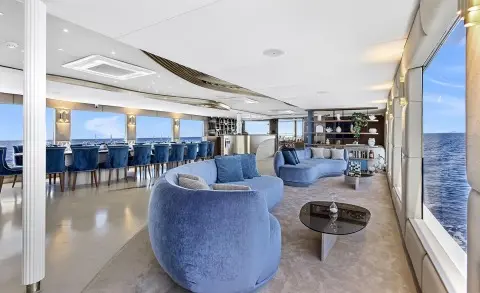 Spacious yacht Bella salon with blue chairs, white counters, and large windows