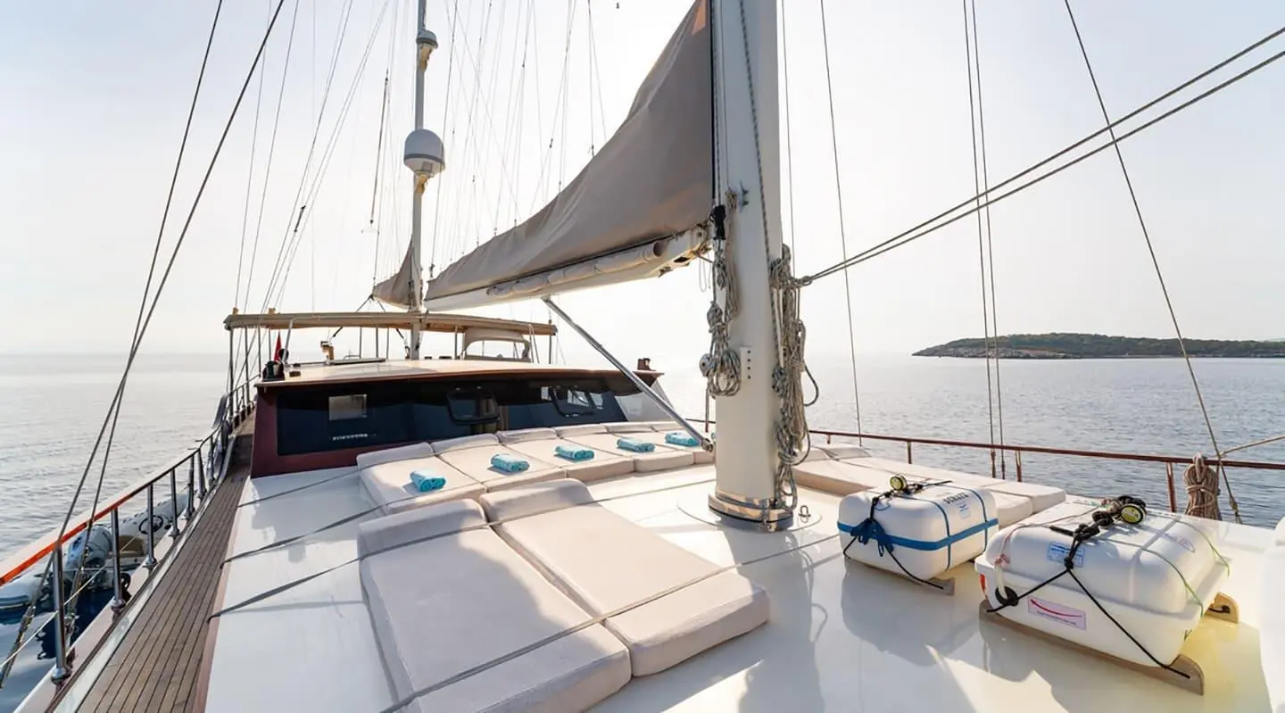 Deck view of a luxury gulet at sunset with sails, calm sea, and yacht Mein Schatz