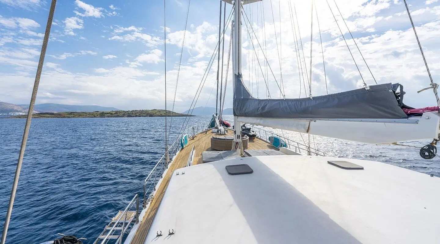 Bow deck of gulet Lucky You with white surface, railing, and blue sea horizon