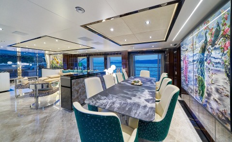 Salon aboard Happy Me motor yacht with dark upholstered chairs and dining table