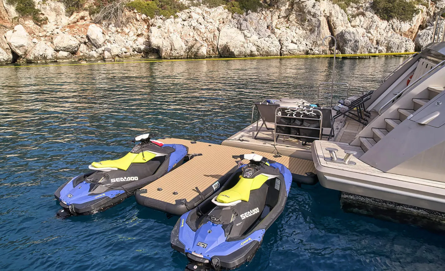 La Pellegrina 1 yacht docked near rocky shoreline with jetskis and small boats