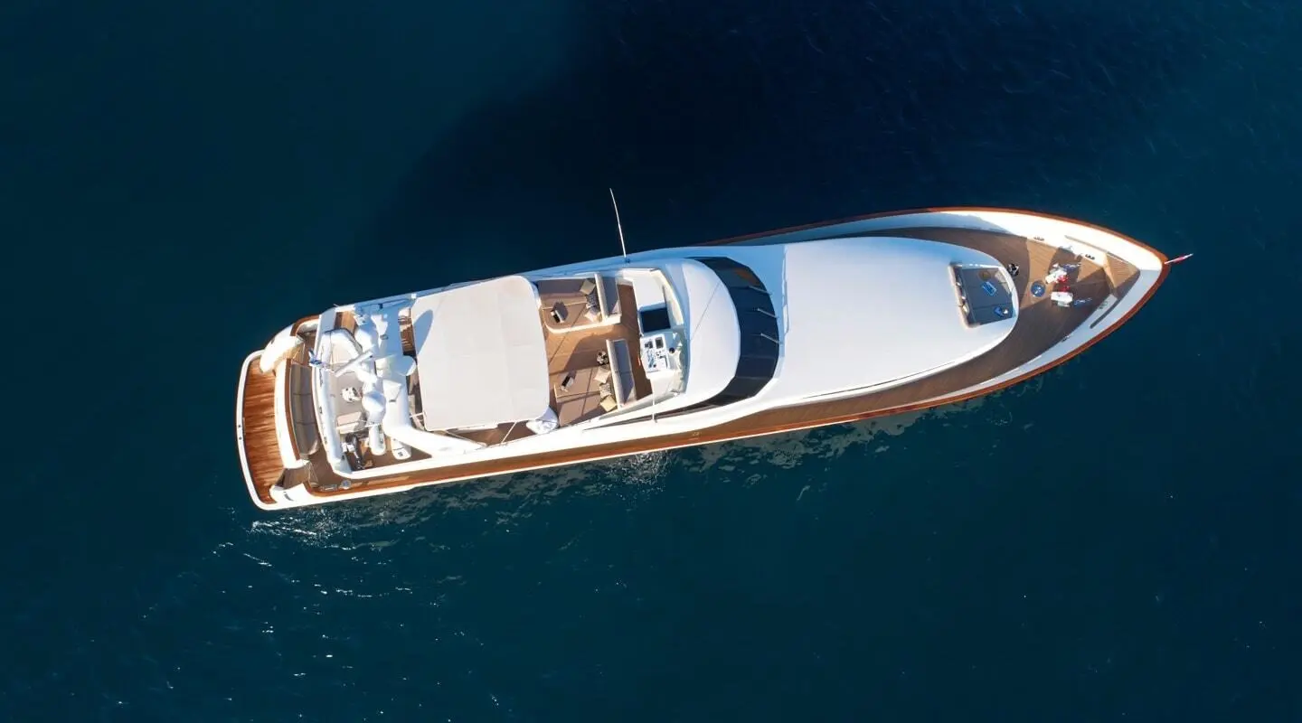 Aquila luxury yacht seen from above cruising on calm blue water, sunlit deck