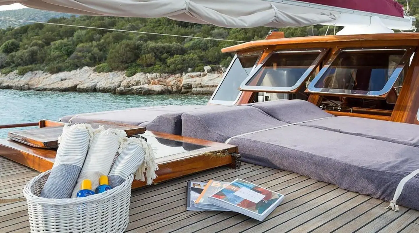 Yacht Primadonna sun deck with seating, cushions, and a blue striped boat nearby