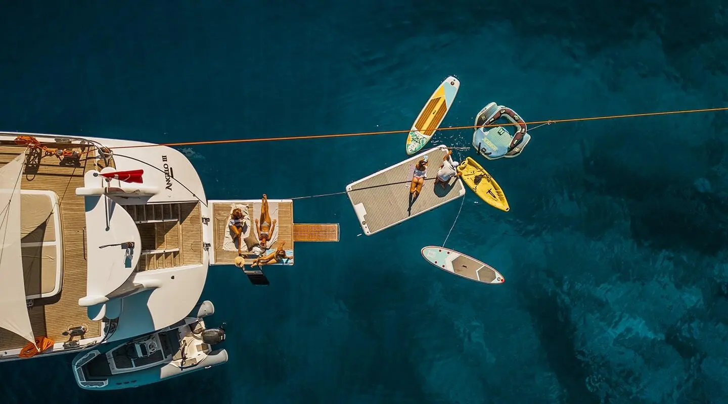 Viewed from above, a luxury gulet anchored in turquoise water at sunset