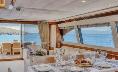 Luxurious yacht dining area with table set, chairs, and windows overlooking sea