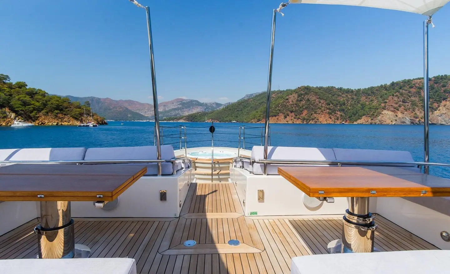 Takara One yacht deck with white seating, wooden tables, and blue sea backdrop