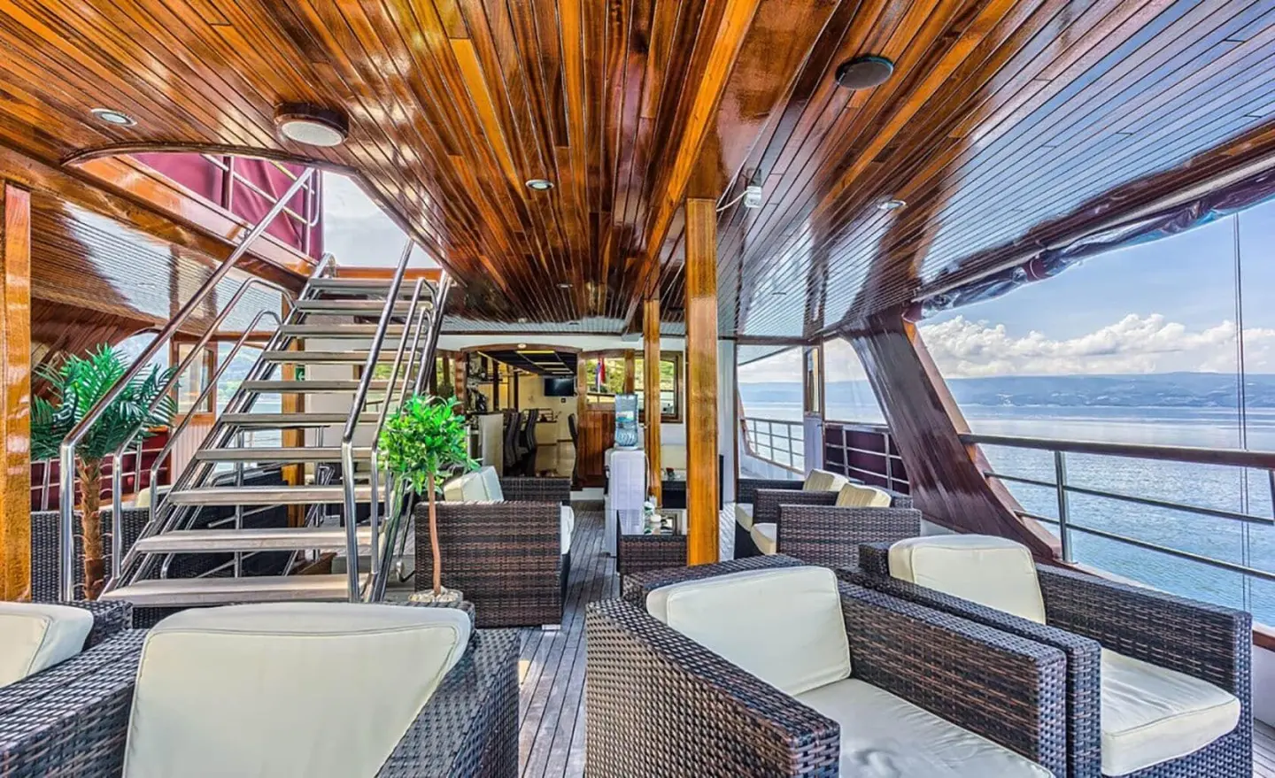 Luxurious yacht Melody deck lounge with wicker seating and wooden ceiling beams