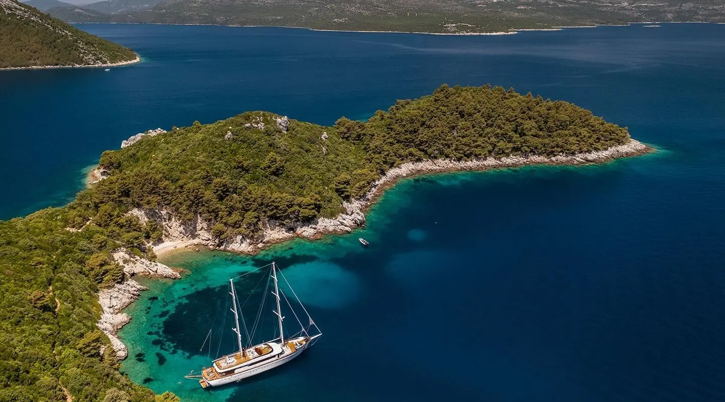 A luxury gulet named Love Story anchored near a sandy cove with a sailboat nearby at sunset