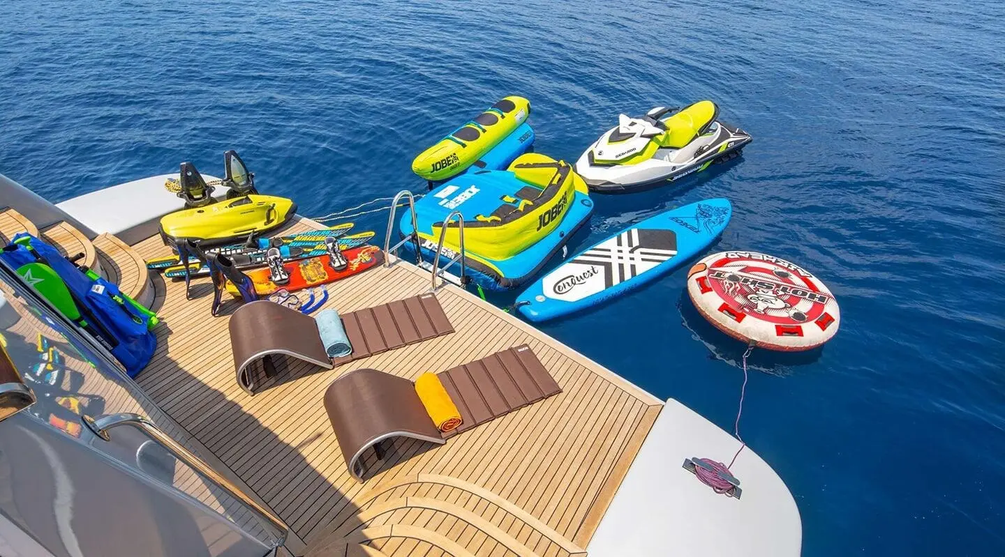 Grace yacht deck with lounging area and colorful watercraft on blue sea