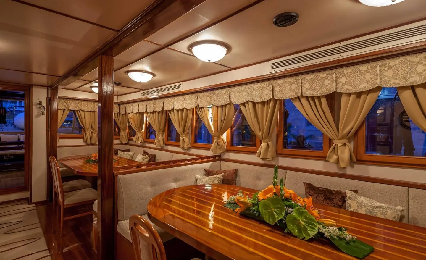 Romanca yacht interior on a carved wooden table with flowers and seating