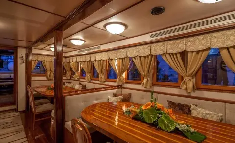 Romanca yacht interior on a carved wooden table with flowers and seating