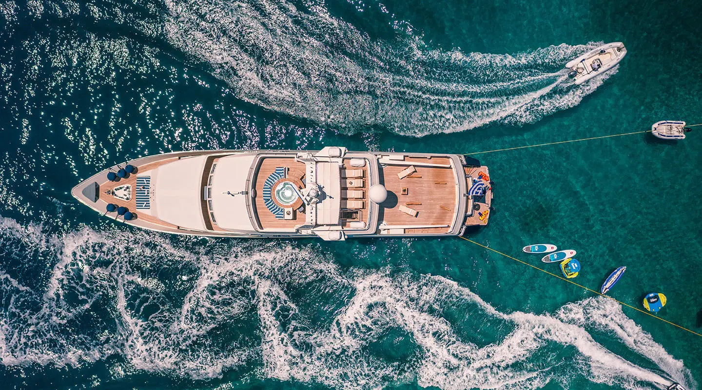 A luxurious white yacht named Magix viewed from above cruising on turquoise water