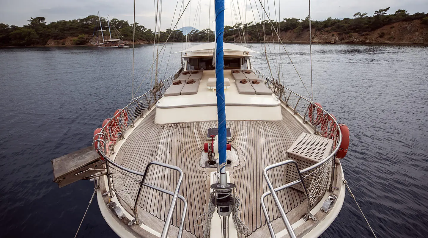 View from the bow of a gulet with wooden deck, ropes, and river water