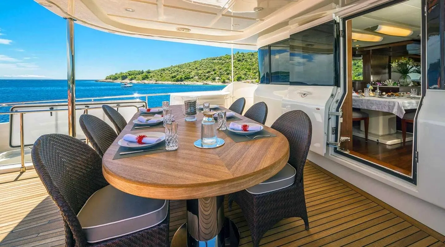 Seventh Sense luxury yacht deck dining area with round table and chairs at sunset