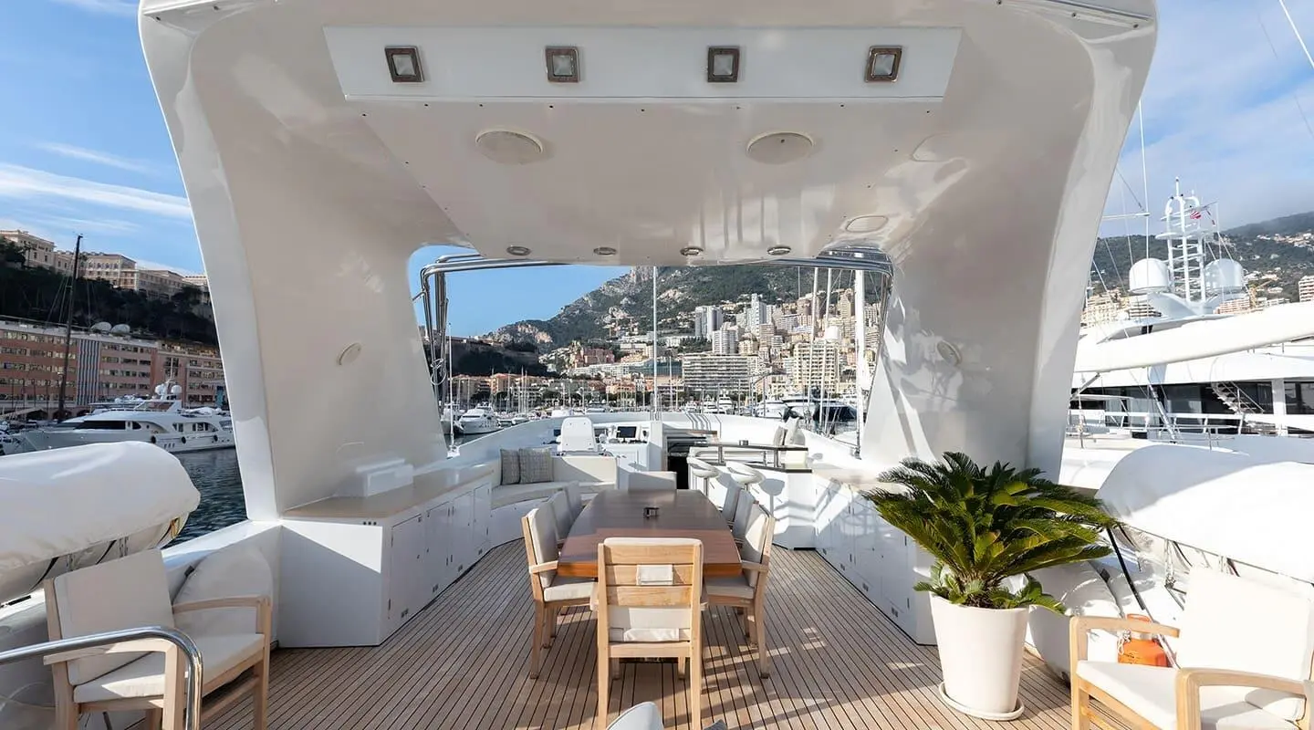 Yacht Brooklyn deck dining area with table, chairs, and potted plants, overlooking marina
