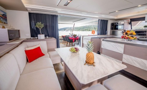 Astoria motor yacht saloon with white sofa and coffee table; large windows letting in natural light