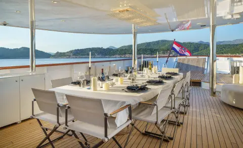 Maia yacht dining area on the open deck with tables and chairs