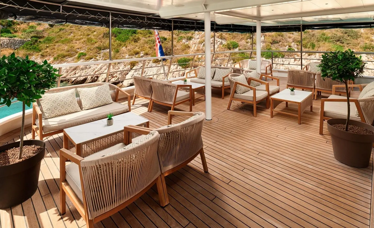 Lupus Mare yacht deck lounge with woven chairs and sun umbrellas