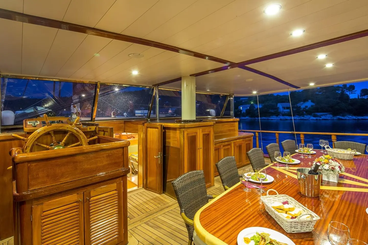 Nighttime aft deck of Morning Star gulet with wooden furniture and string lights