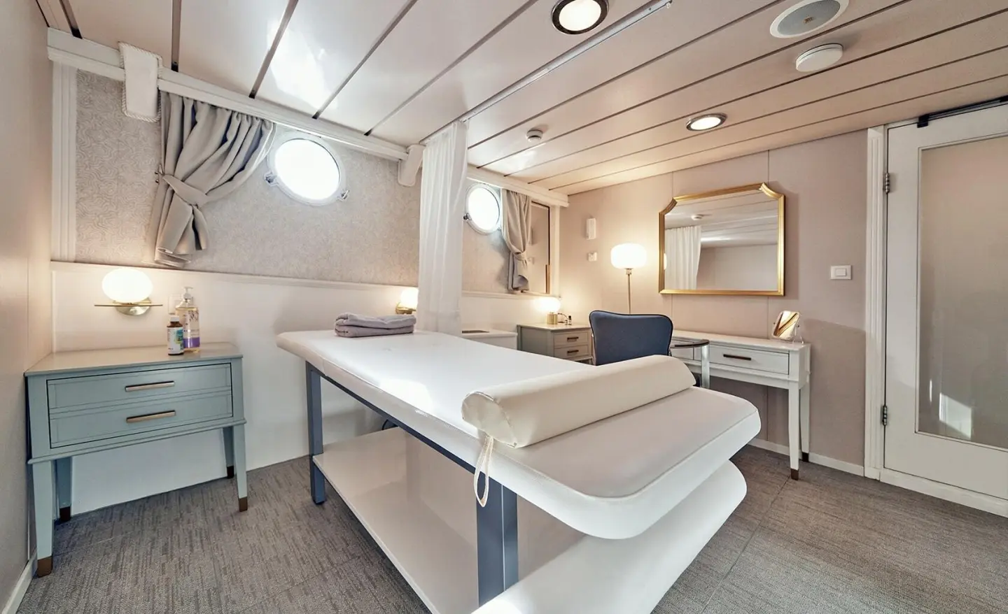 Massage room on La Perla yacht with a long table and seating