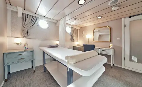 Massage room on La Perla yacht with a long table and seating