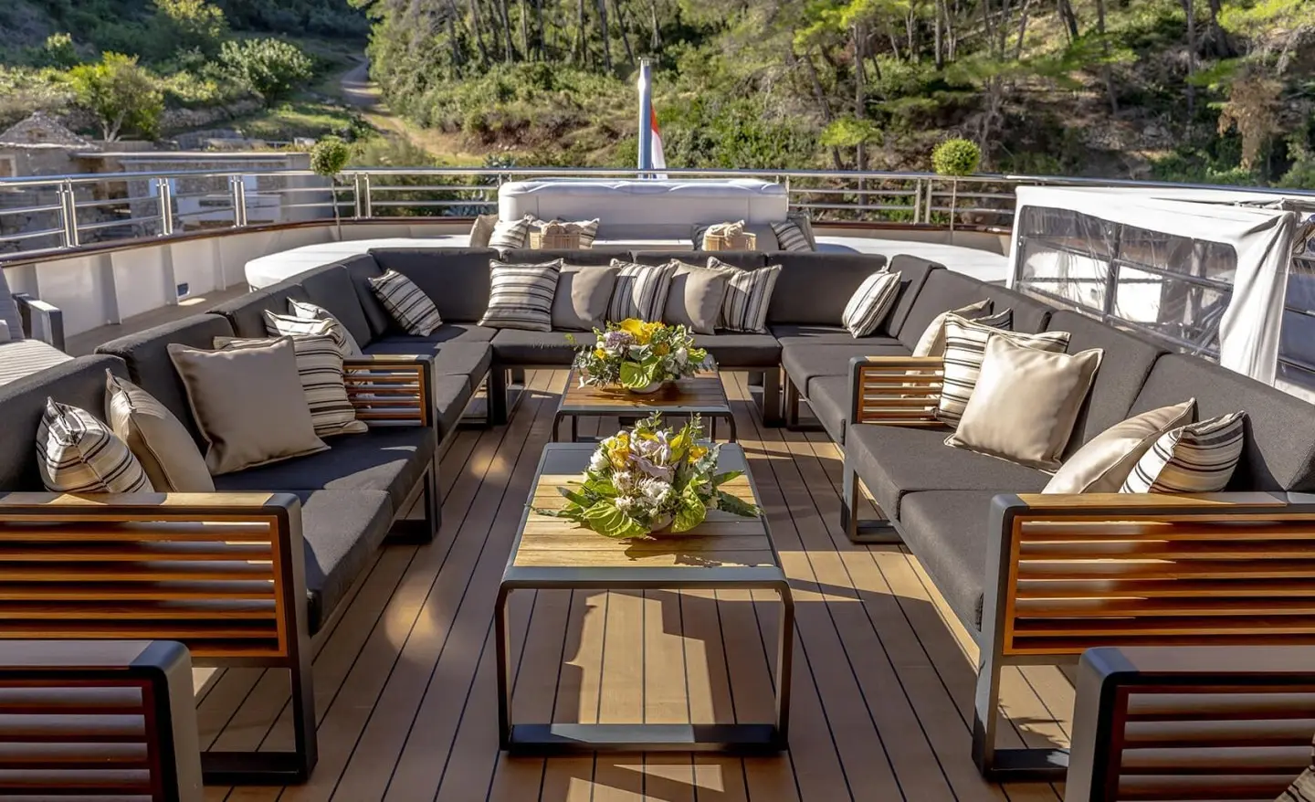 Aboard Freedom yacht sun deck with cushioned seating, table, and greenery
