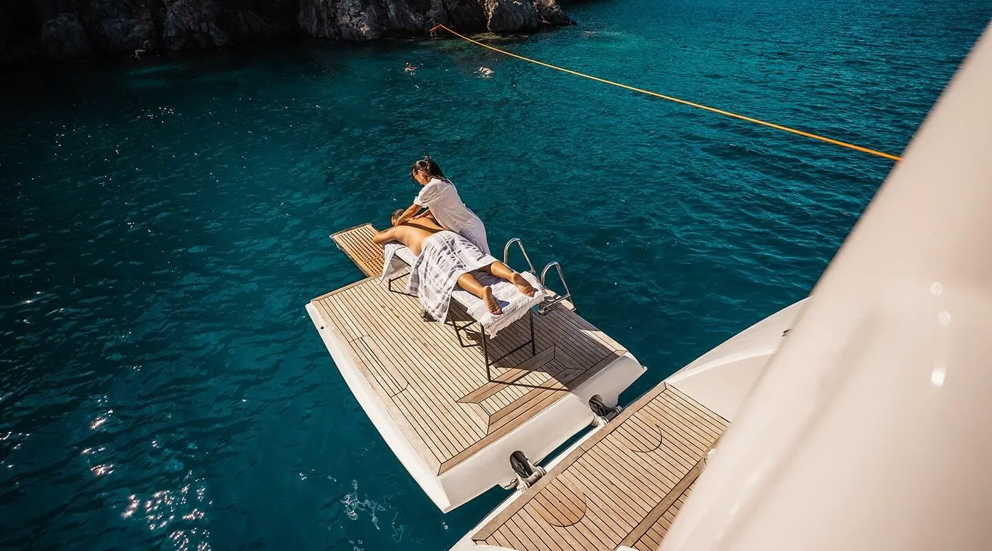 Top-down view of Angelo III yacht anchored near rocky coast at sunset
