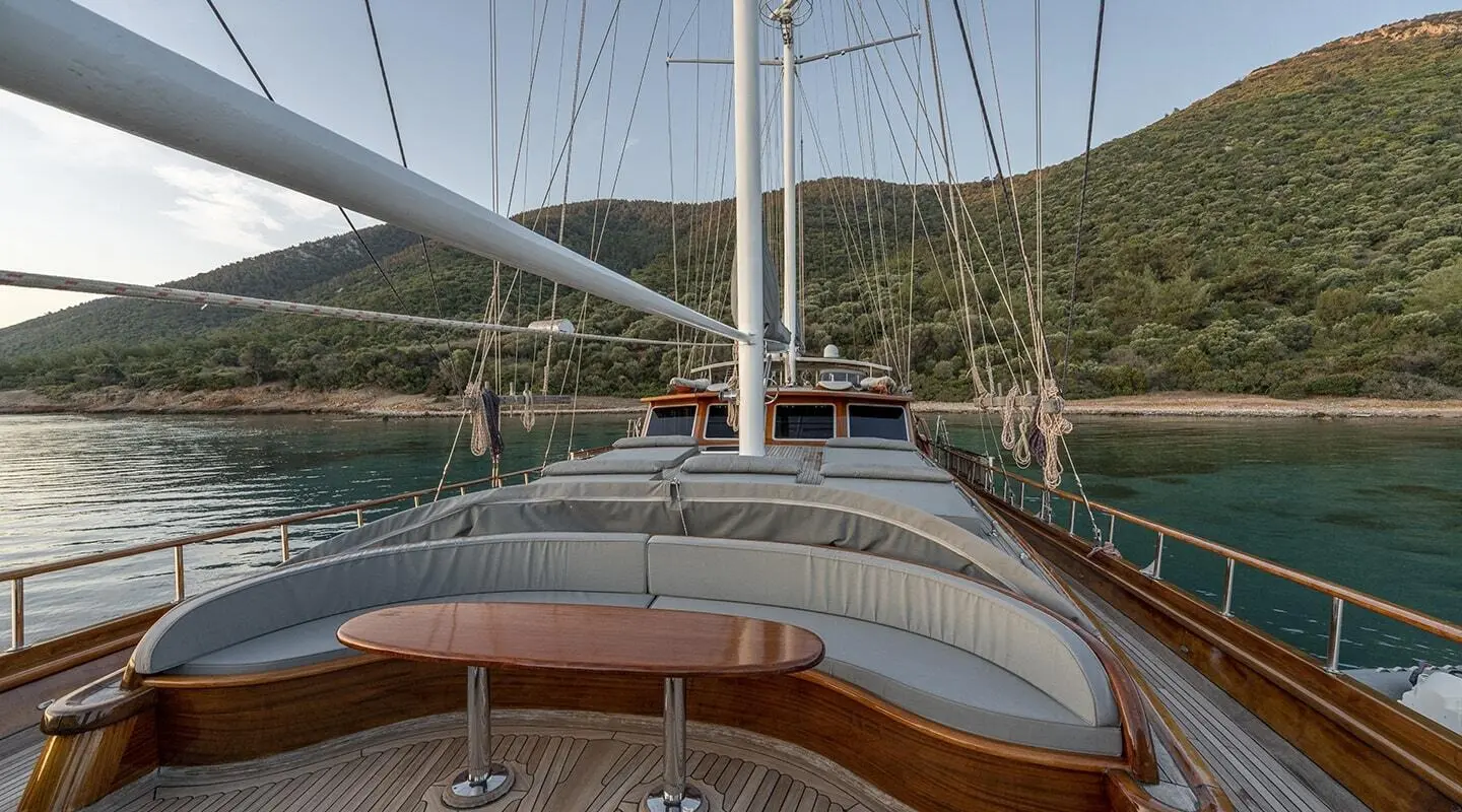 Large seating area on the deck with a wooden table, amidship yacht and calm water