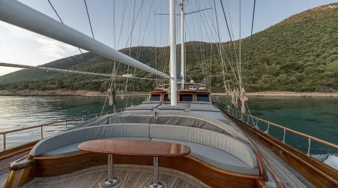 Large seating area on the deck with a wooden table, amidship yacht and calm water