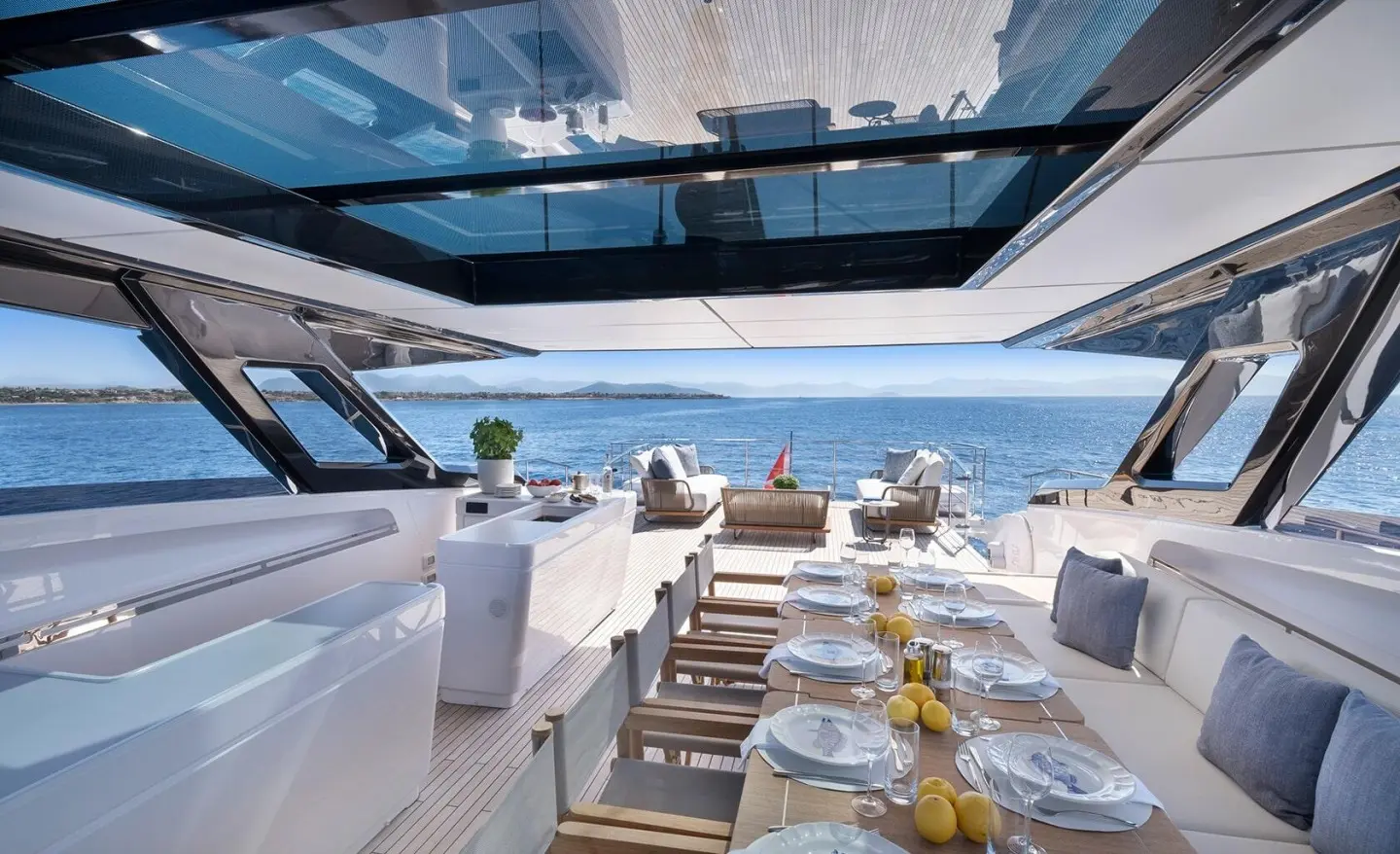 Spica yacht deck dining area with white seating, sunlit tables and stairs