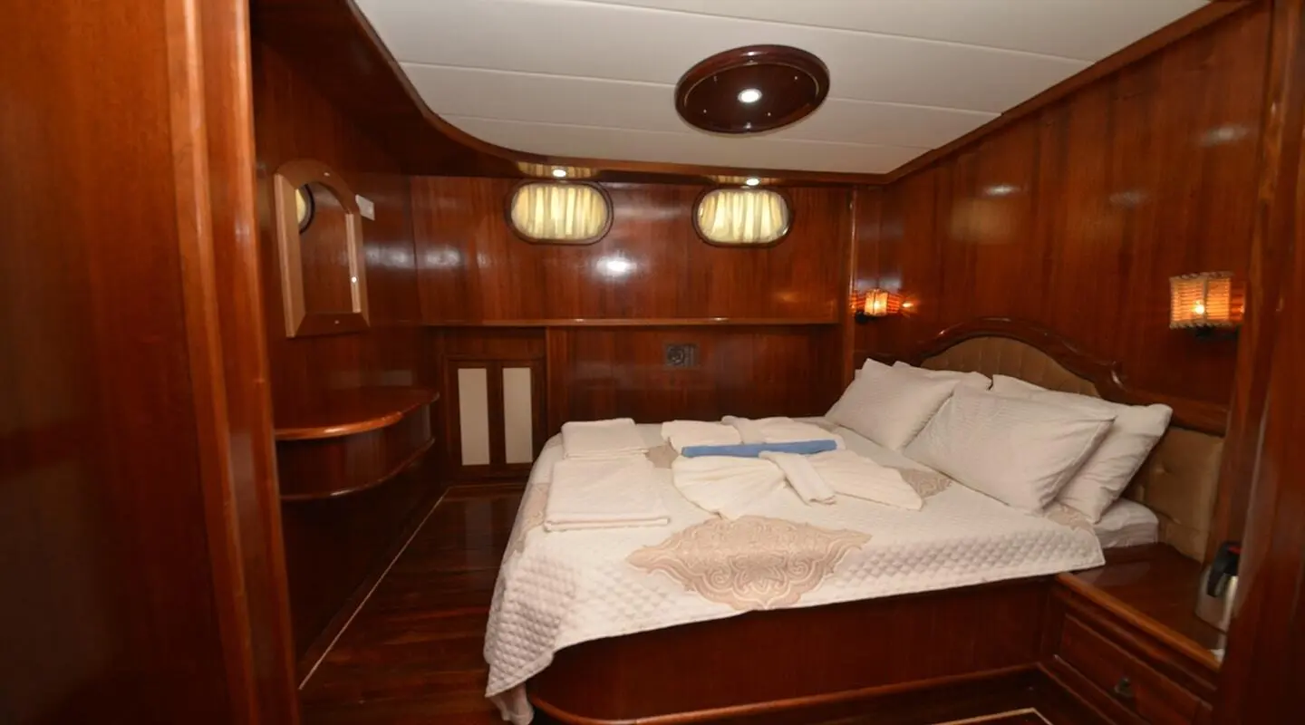 Interior view of a wooden yacht cabin with a double bed and built-in cabinets
