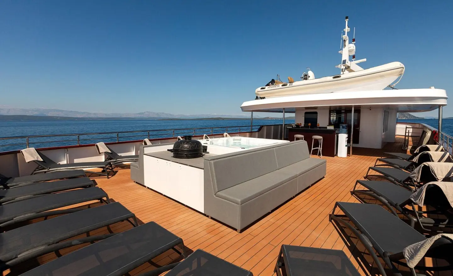 Yolo yacht deck with loungers and a hot tub on a sunny open-air aft terrace