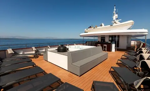 Yolo yacht deck with loungers and a hot tub on a sunny open-air aft terrace