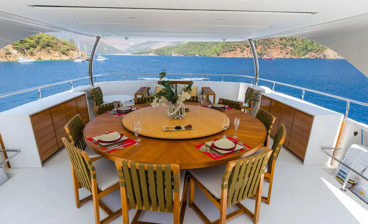 Takara One yacht dining area with round table and wooden chairs on deck